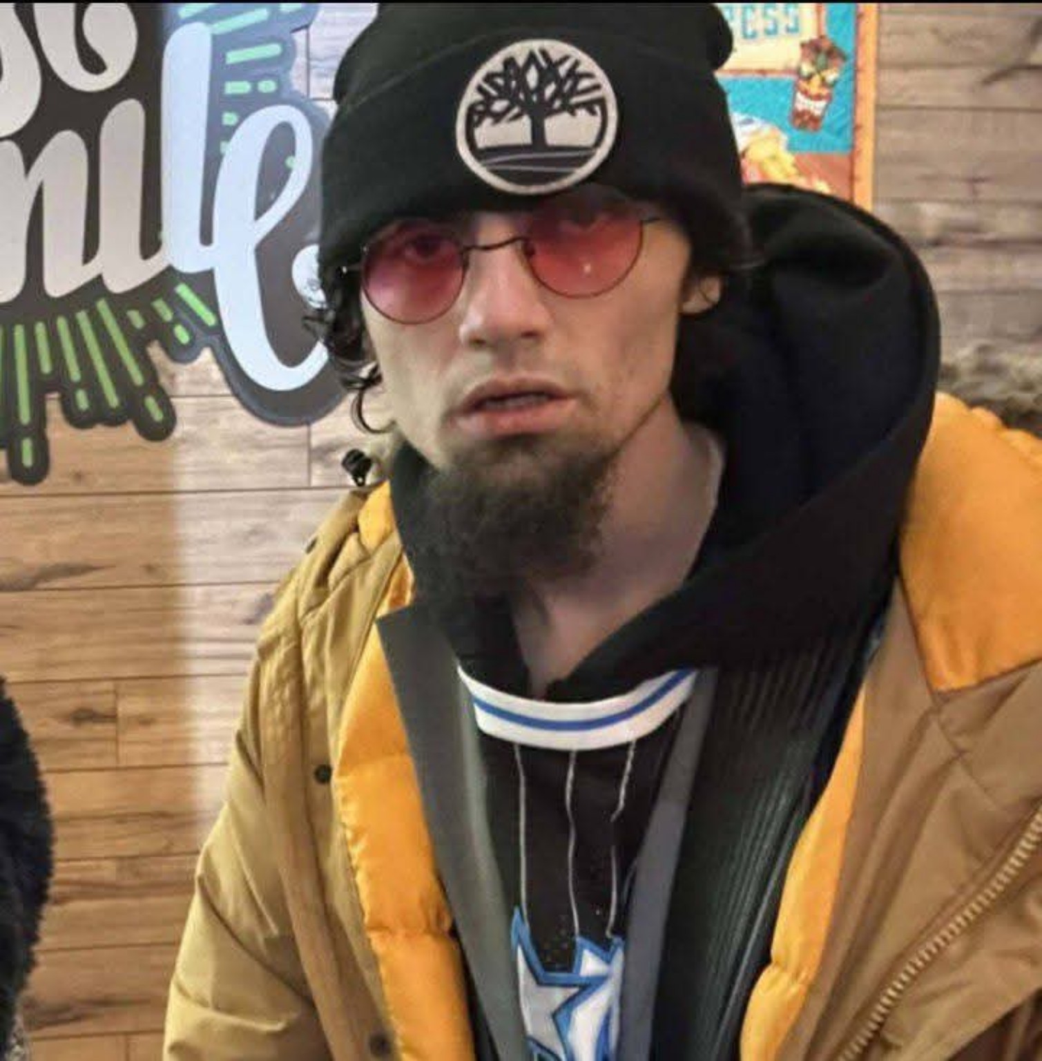Scumbag Rick wearing a beanie, tinted glasses and a yellow jacket